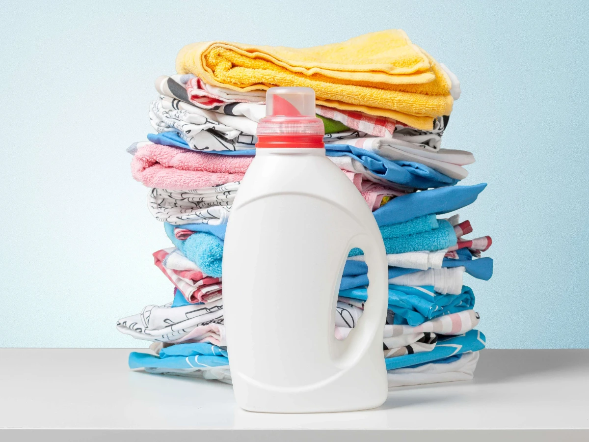  Waschmittel mit bunten Handtüchern im Hintergrund 