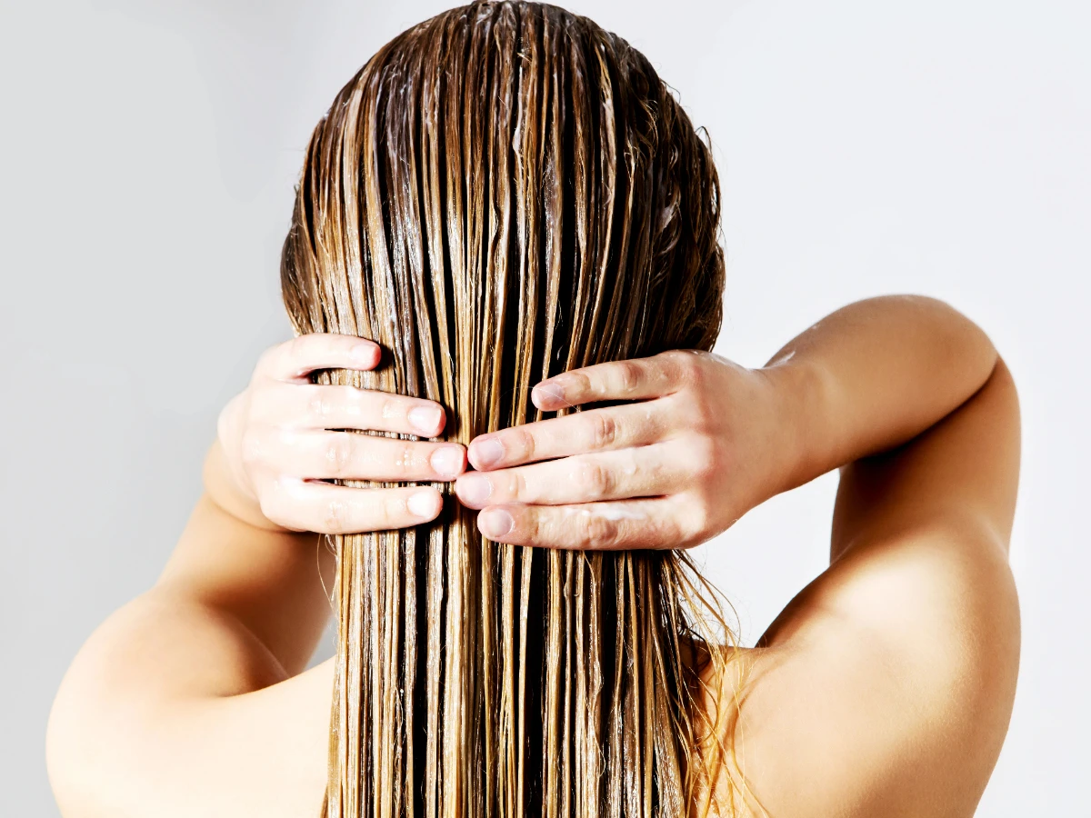  Frau wendet Haarkur Haarmaske an auf nassen Haaren 