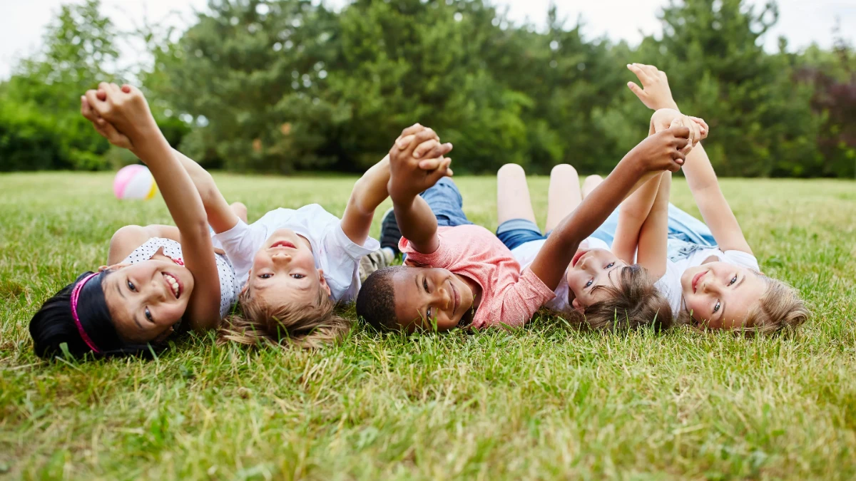  Mehrere Kinder liegen auf einer Wiese 