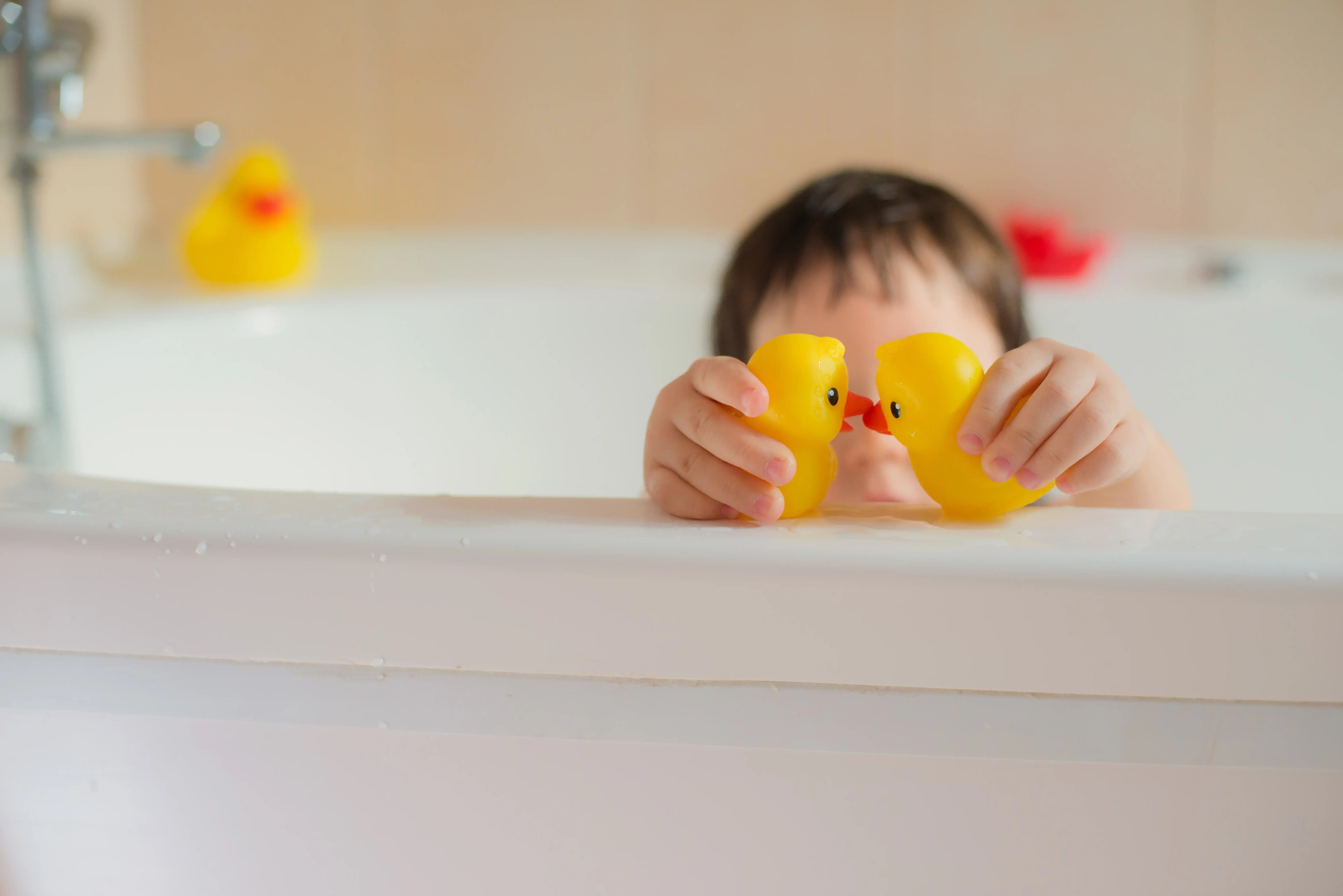  Kind spielt mit Gummiente in der Badewanne 