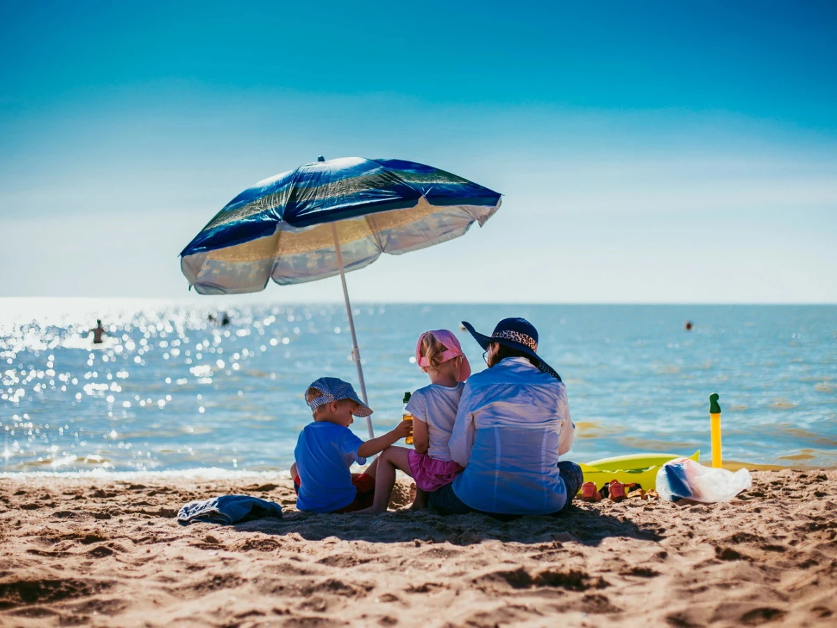  Familie am Strand mit Sonnenschirm 