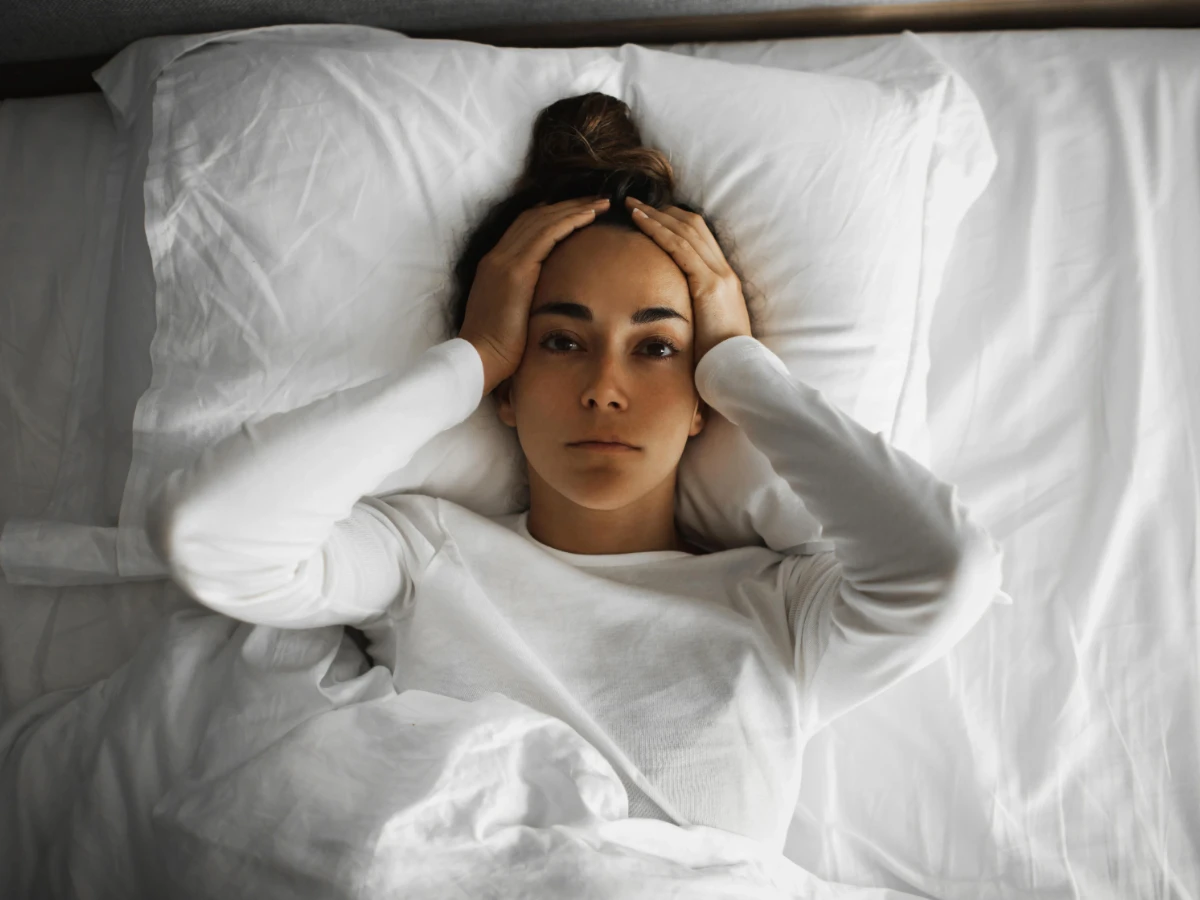  Frau liegt schlaflos im Bett 