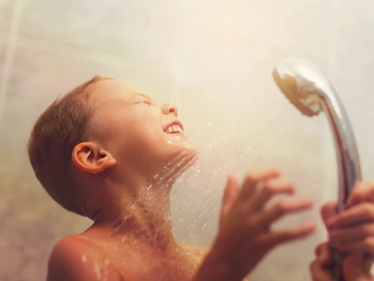  Kind hält Duschkopf 