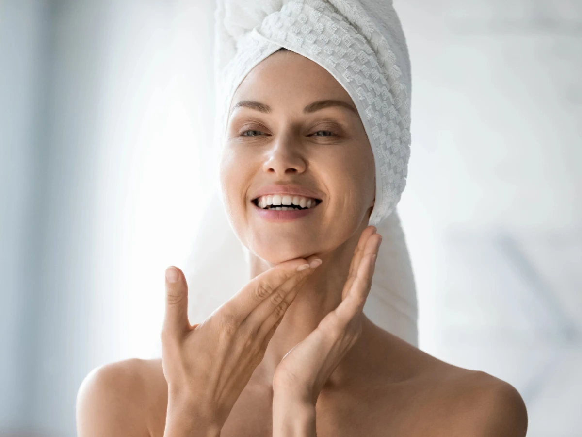  Frau im Badezimmer, trägt Selbstbräuner im Gesicht auf. 