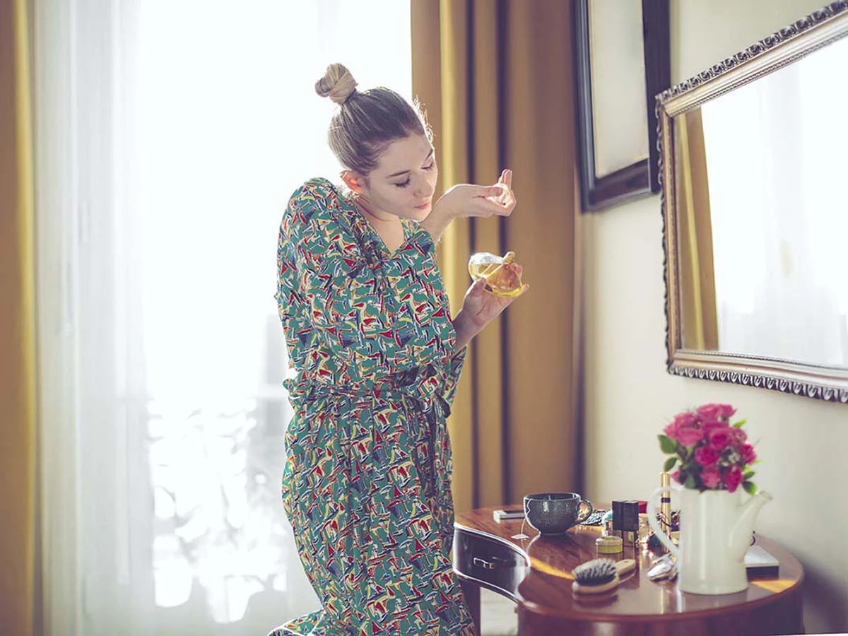  Frau sprüht Parfum auf ihr Handgelenk 