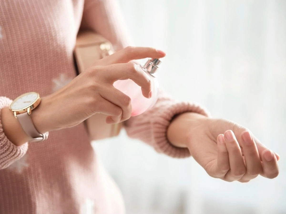  Frau sprüht Parfum auf ihr Handgelenk 