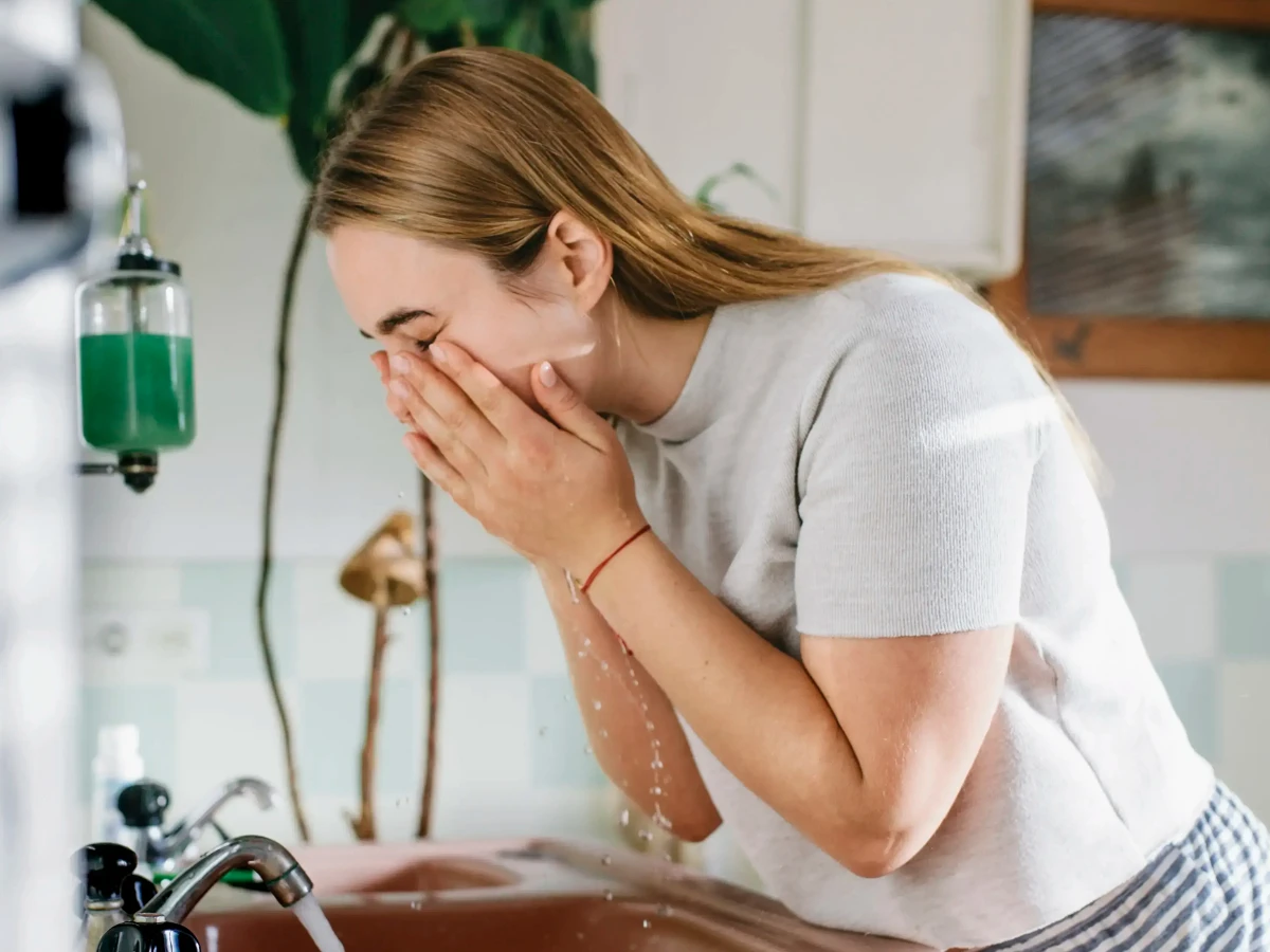  Junge Frau wäscht sich das Gesicht im Badezimmer 