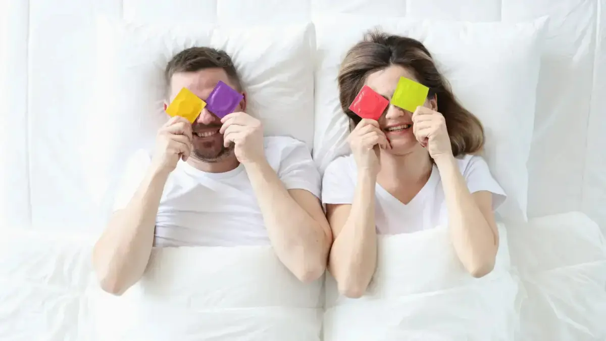  Pärchen im Bett mit bunten Kondomen 
