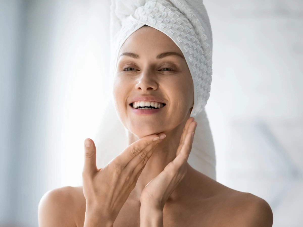  Frau im Badezimmer, trägt Selbstbräuner im Gesicht auf. 