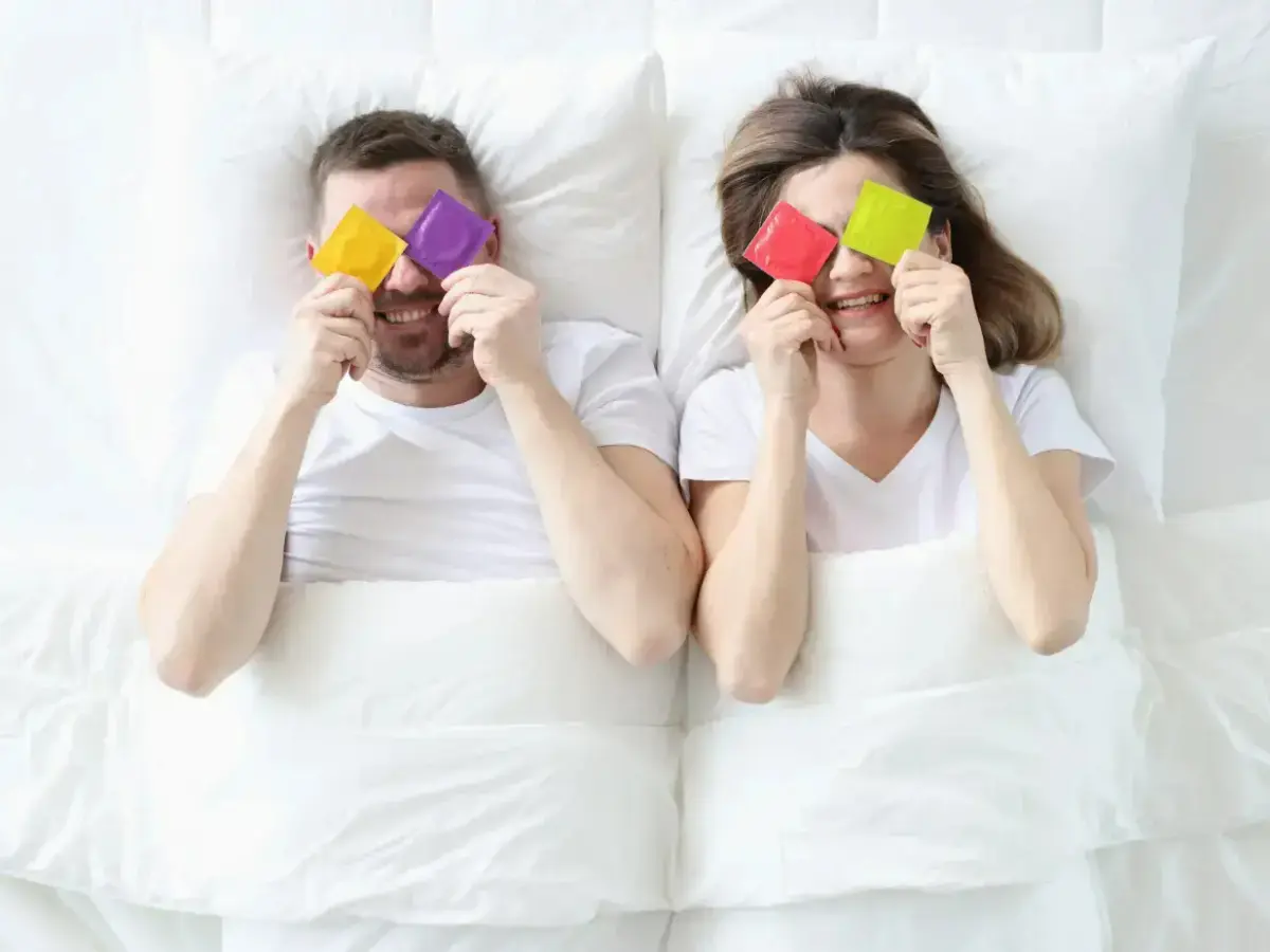  Pärchen im Bett mit bunten Kondomen 