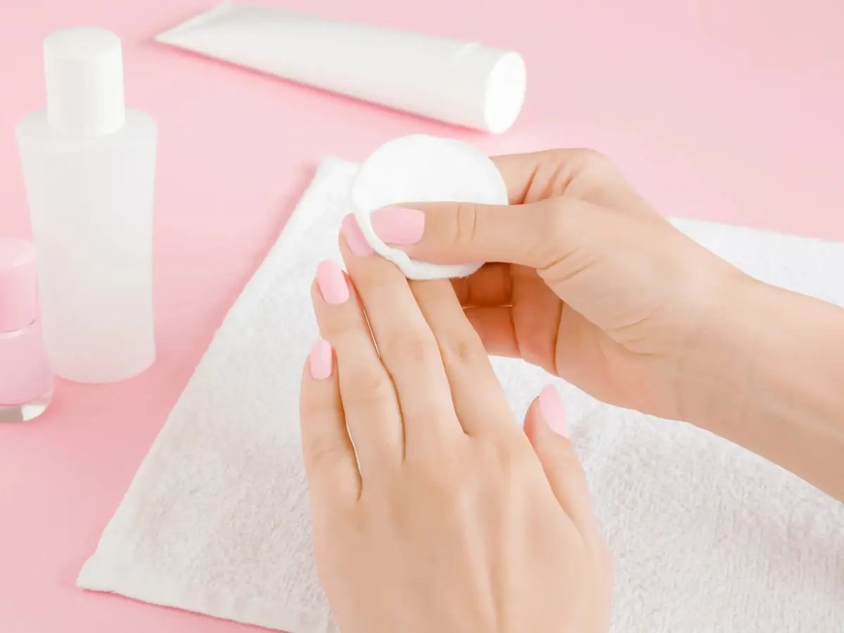  Frau entfernt Nagellack oder Gel von ihren Fingernägeln 