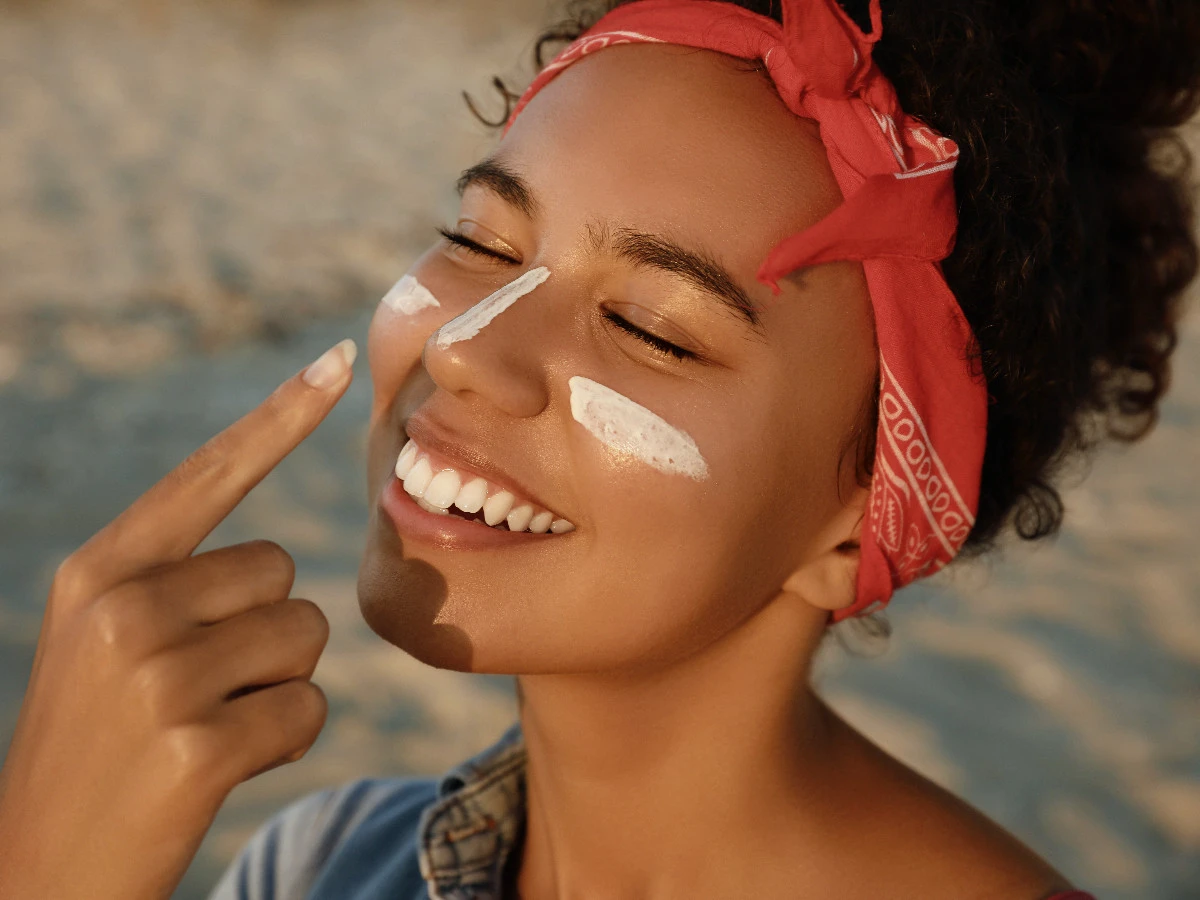  Frau trägt Sonnenschutz im Gesicht auf 