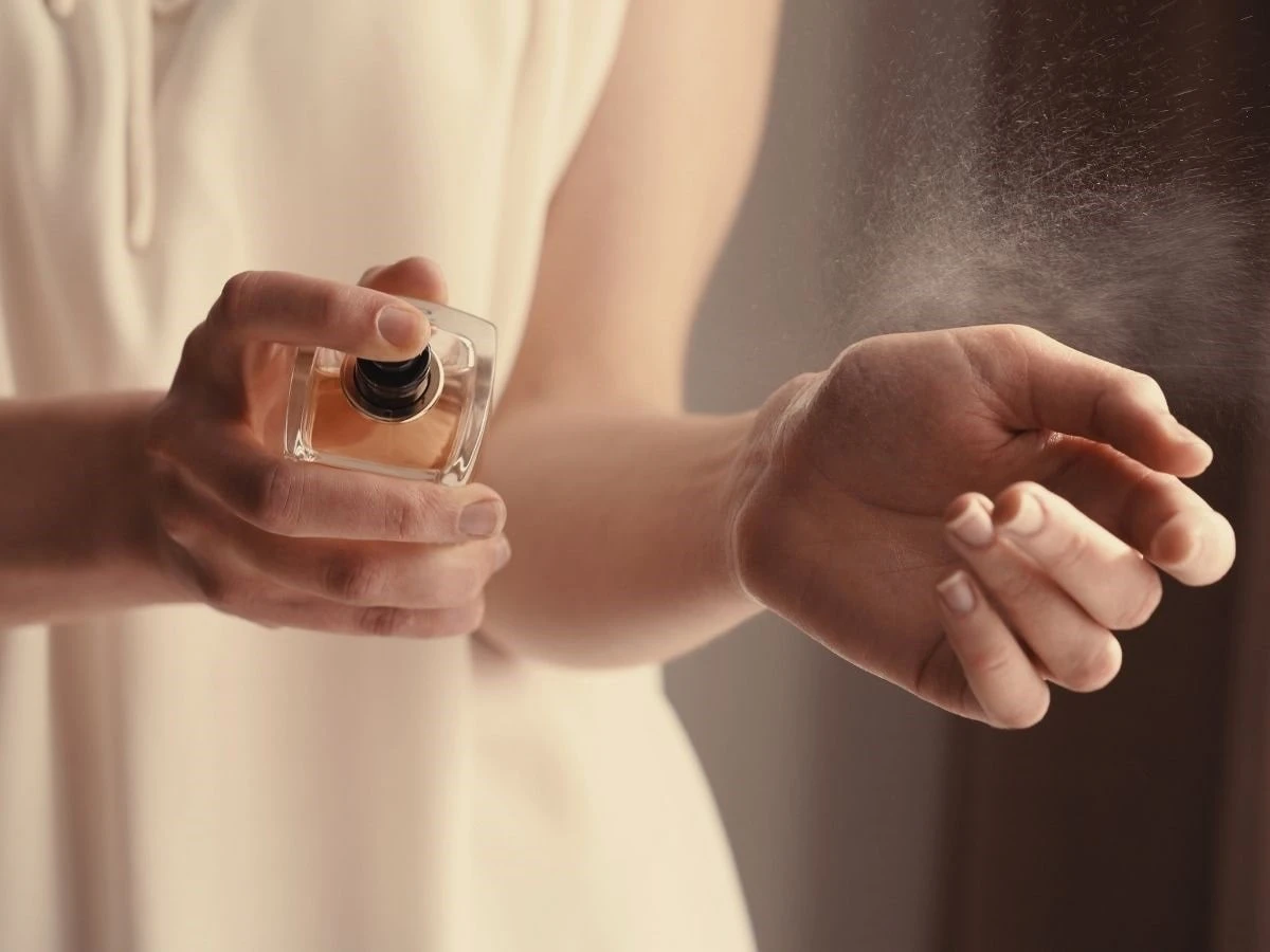  Frau sprüht Parfum auf Handgelenk 