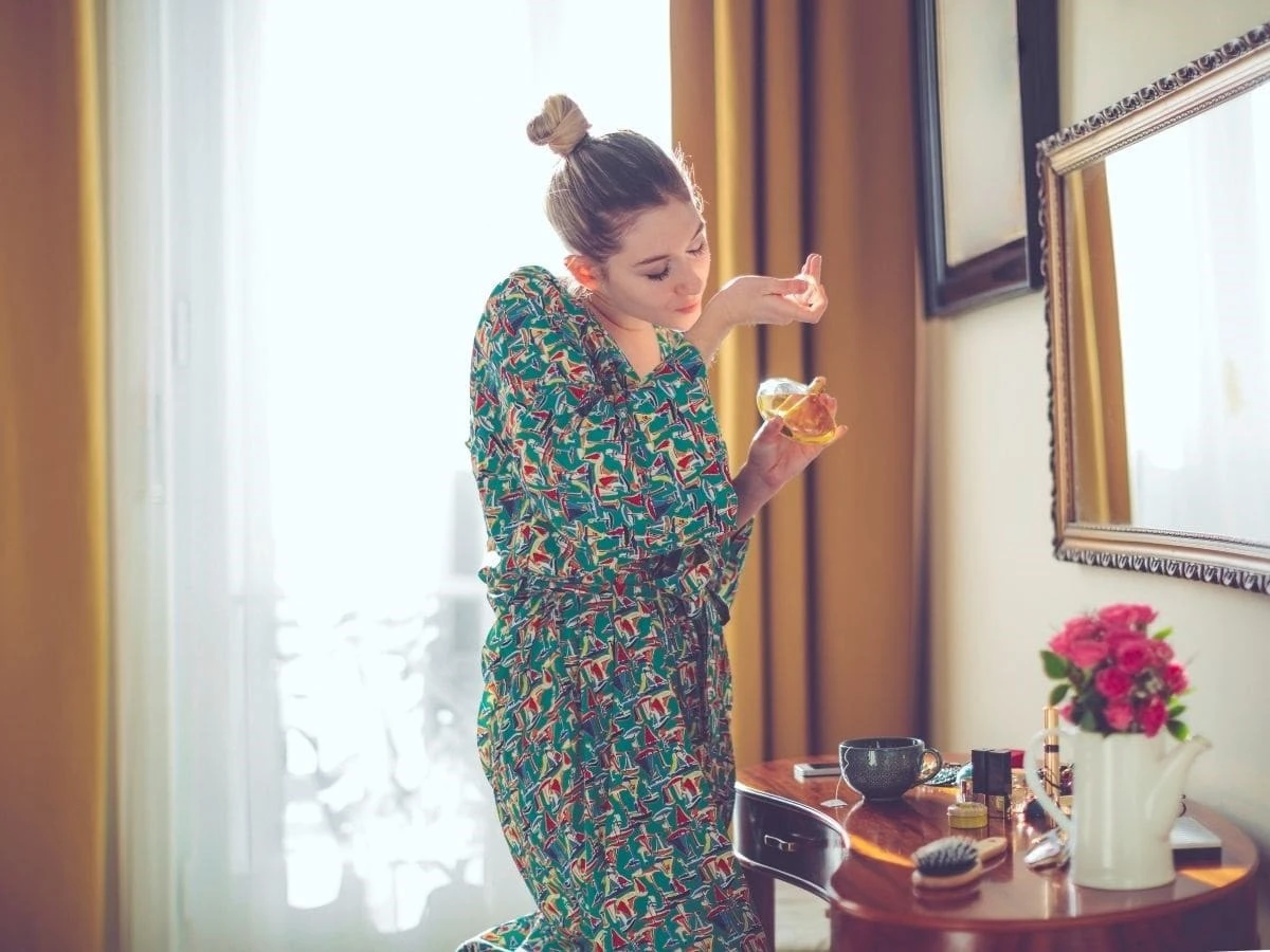  Frau sprüht Parfum auf Handgelenk 