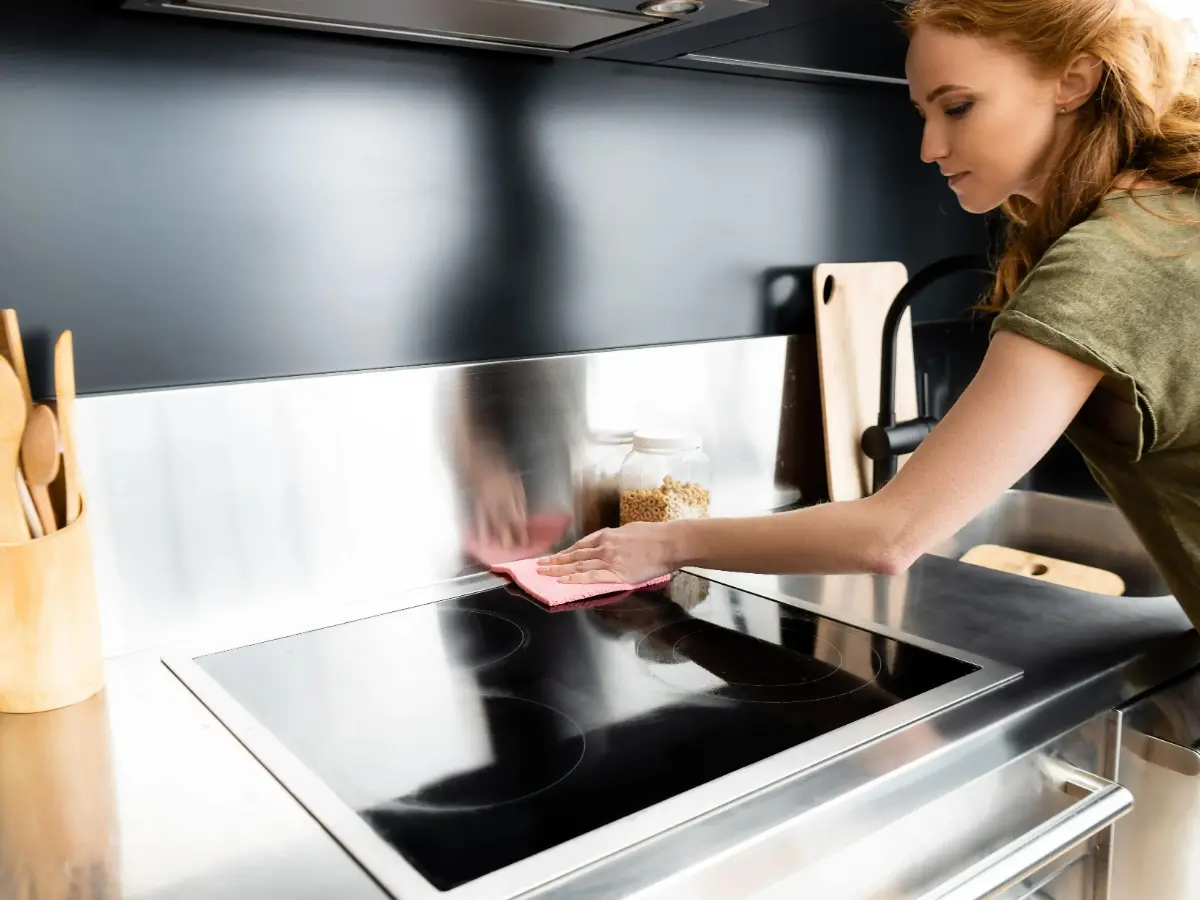  Frau putzt den Herd in der Küche 