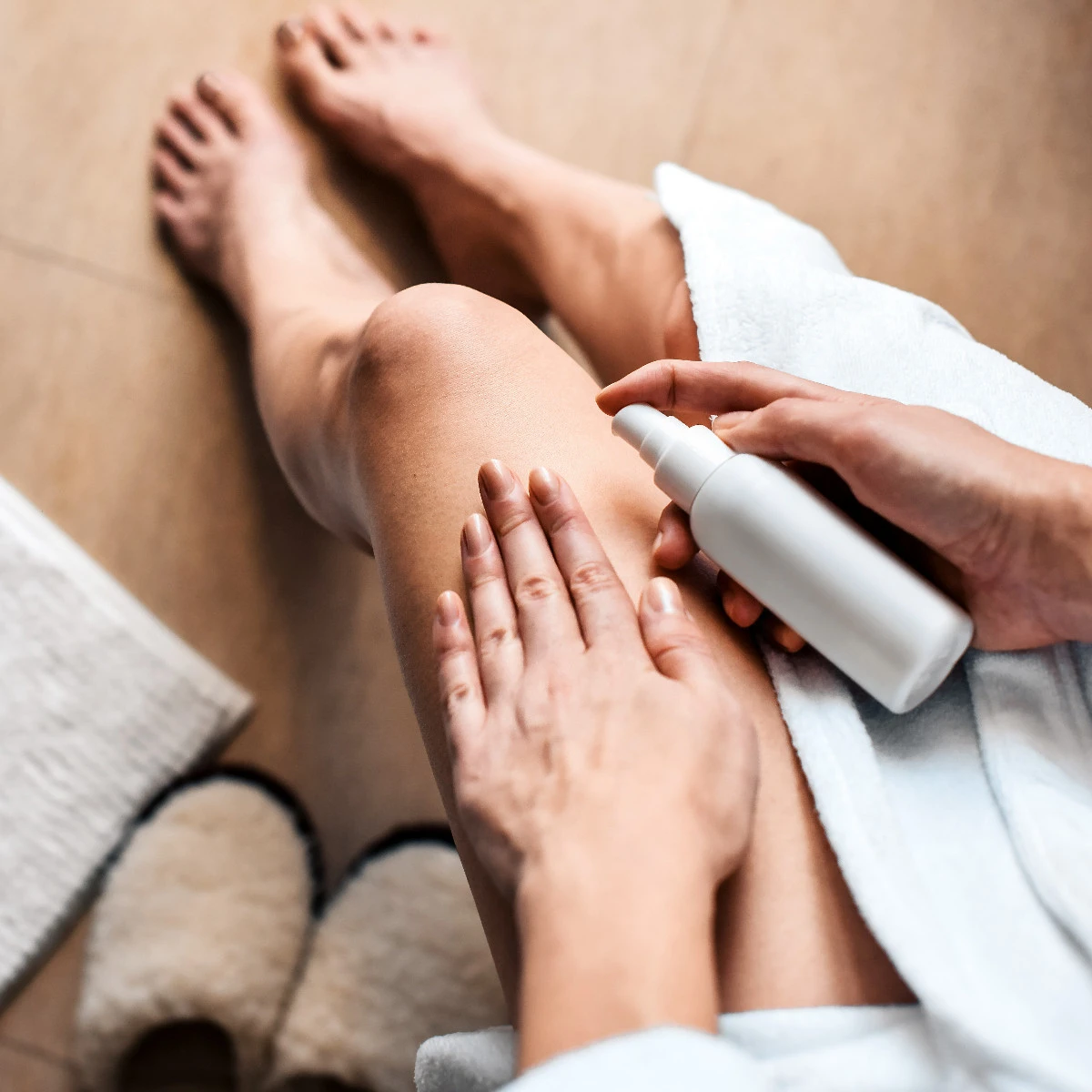  Frau cremt ihre Beine mit Lotion ein 