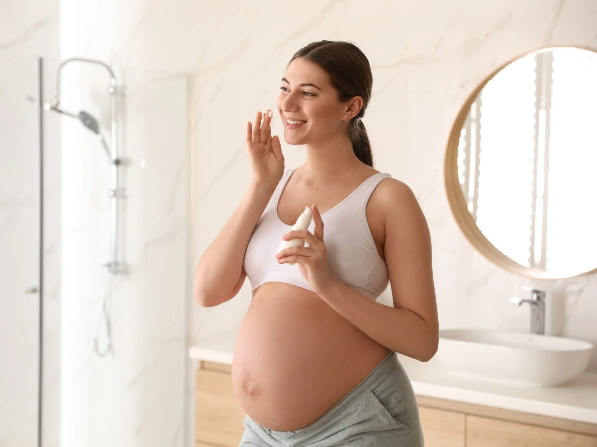  Schwangere Frau trägt Gesichtspflege auf 
